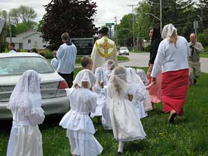 children in white processing with priest