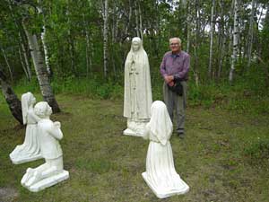 Parishioer stands next to life size statures of Fatima apparition