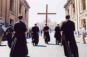 Text Box: Carrying a big cross, Bishop Fellay leads the procession, drawing near St. Peters Square
