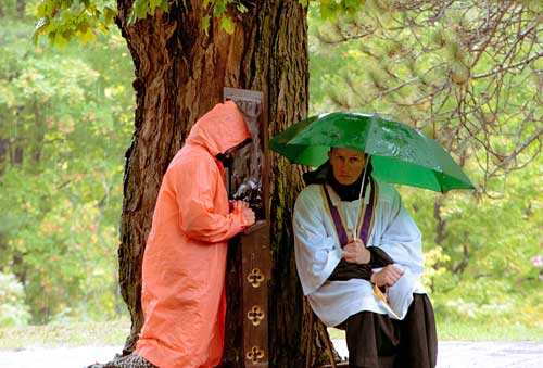 Priests hears confession in rain during pilgrimage